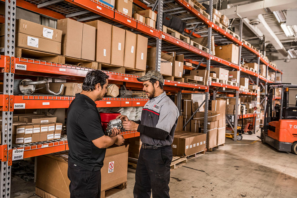 A parts specialist discussing forklift parts with a customer in front of parts shelves
