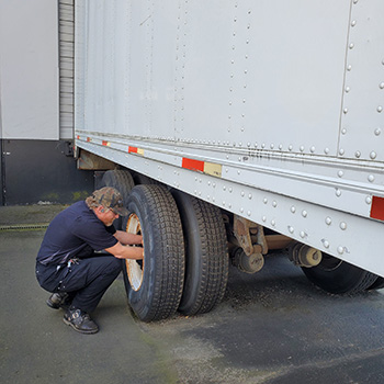 A trailer service technician inspecting a trailer wheel