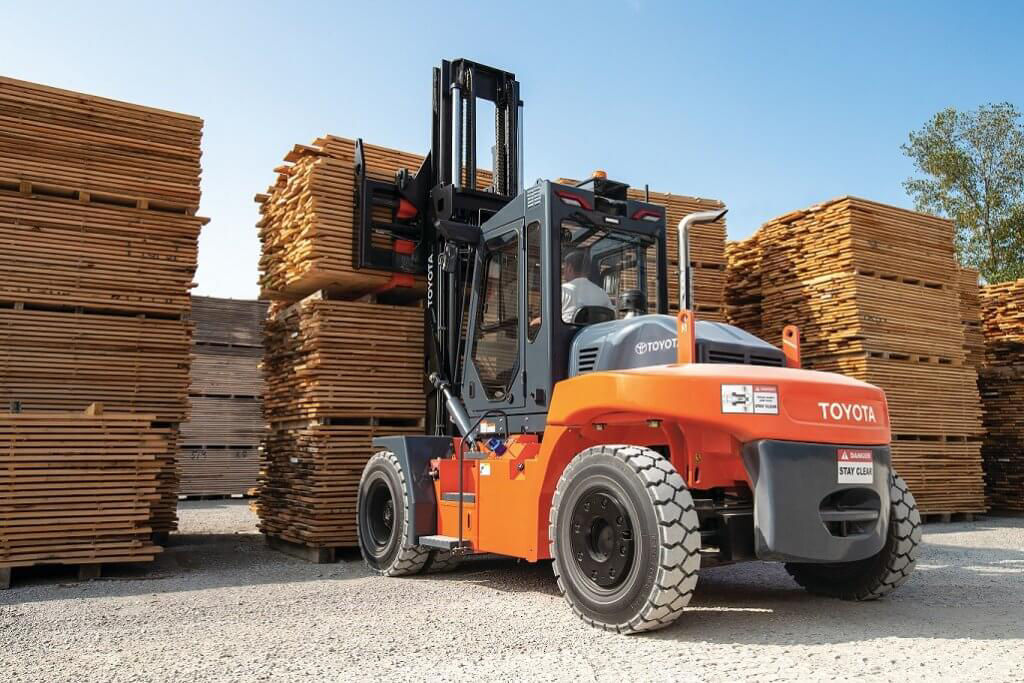 A high-capacity Pneumatic Tire forklift carries lumber outdoors